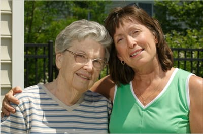 Senior resident and caregiver sharing a smile outdoors.