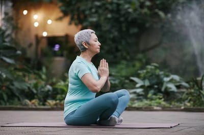 Senior woman practicing yoga in a garden