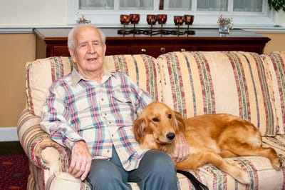 Elderly resident with a golden retriever on a couch