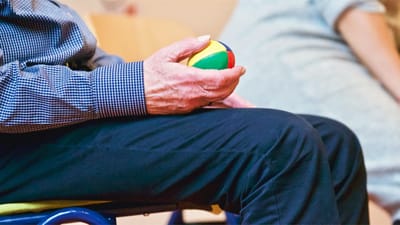 A resident holding a multi-colored stress ball during an activity