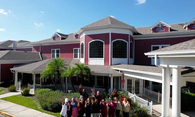 Staff and residents happily posing outside the facility.