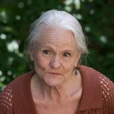 Close-up of an elderly woman smiling outdoors.
