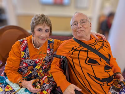 Two residents in festive sweaters enjoying time together.