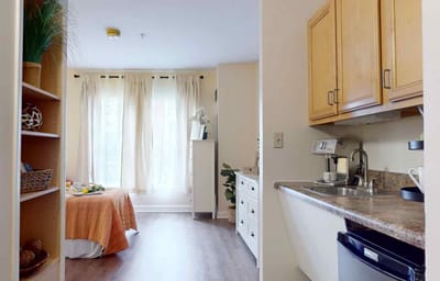 Cozy resident room with kitchenette and natural light.