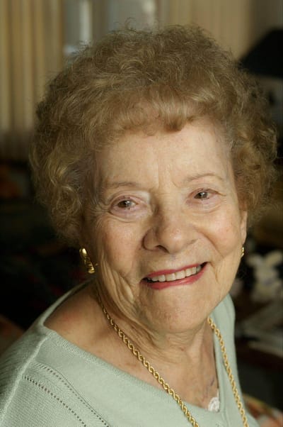 Smiling elderly woman in a cozy interior setting.
