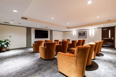 Cozy common area with orange chairs and a TV.