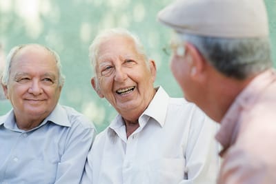 Three seniors laughing and chatting outdoors.