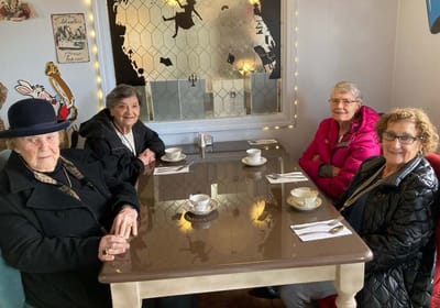 Four women enjoying tea at a dining table.