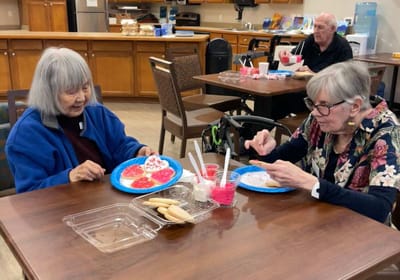 Two residents decorating cookies during an activity.