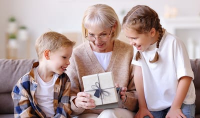 Grandmother opening a gift with two children