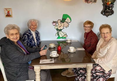 Four women enjoying tea at a dining table.
