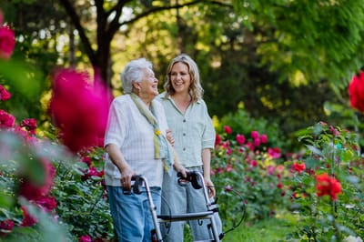 Senior woman enjoying a garden walk with her caregiver.