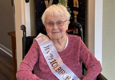 Resident celebrating her 101st birthday with a sash.