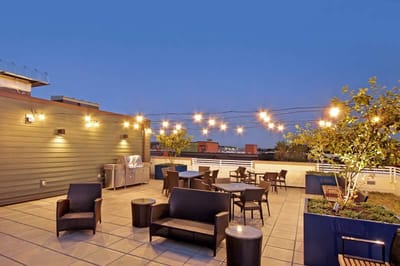 Outdoor patio with lounge seating and string lights.