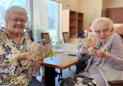 Two residents holding decorated Easter crafts.