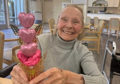 Smiling resident holding a decorative flower arrangement.