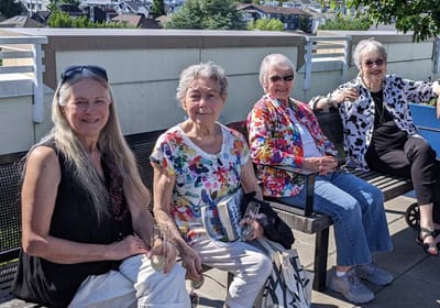 Four women enjoying time outdoors on a bench.