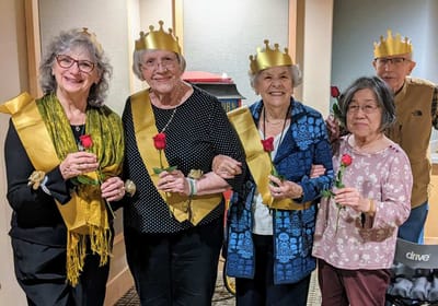 Residents participating in a celebration with crowns and roses.