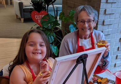 A child and senior woman enjoying an art activity together.