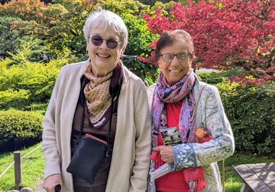 Two smiling senior women enjoying a garden