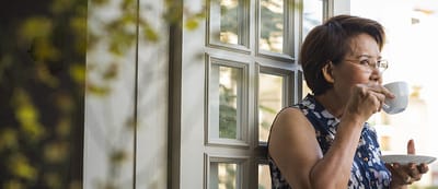 Woman enjoying a cup of tea by a window.