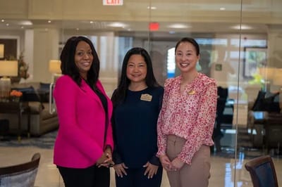 Three staff members in a welcoming lobby area.