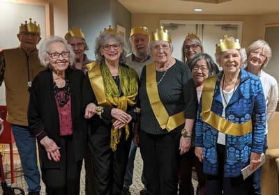 Group of seniors celebrating with crowns and sashes.
