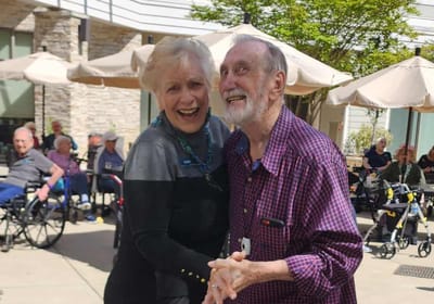 Residents and staff dancing outdoors during an event.