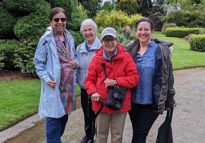 Group of four women enjoying time outside in a garden.