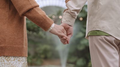 Two hands holding in a garden setting