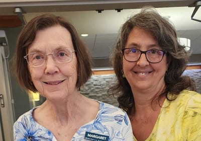 Senior resident and staff member smiling together.
