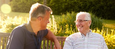 Caregiver and resident smiling in a garden