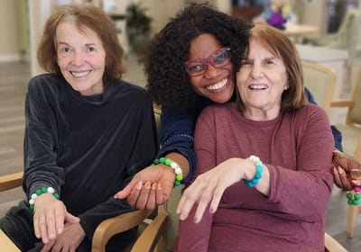 Three women smiling, engaged in an activity together.