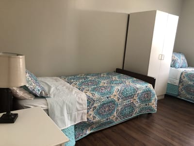 A spacious resident room with two beds and a wardrobe