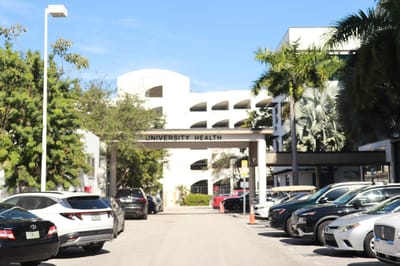 Entrance to University Health building with vehicles parked