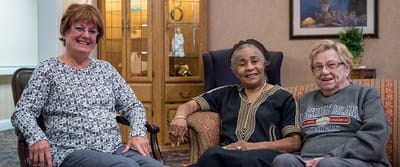 Three residents interacting in a cozy lounge area