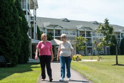 Two residents walking together in a landscaped area