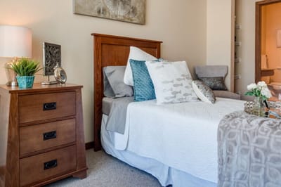 A well-decorated private resident room with a cozy bed
