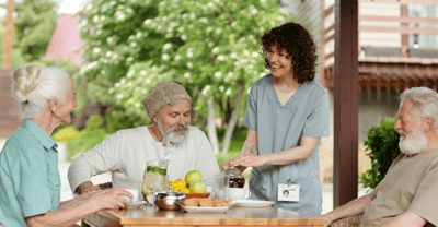 Residents enjoying refreshments with staff in an outdoor setting