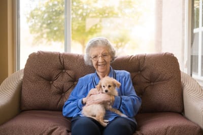 A resident holding a small puppy on a couch