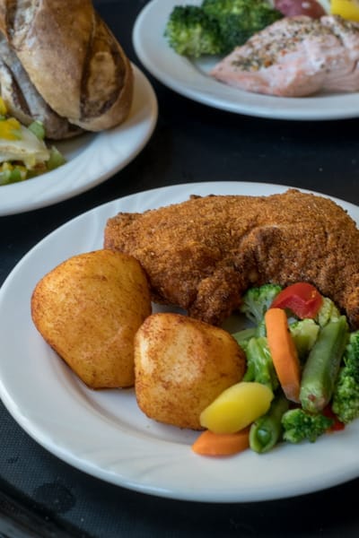 A plated meal featuring fried fish and vegetables