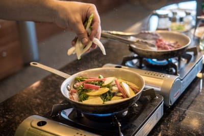 A hand adding ingredients to a skillet in a kitchen