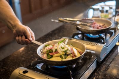 A hand cooking vegetables in a kitchen