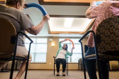Residents participating in a seated exercise class indoors