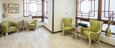 A cozy common area with green seating and large windows
