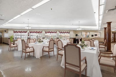 Dining room set up for a meal with tables and chairs