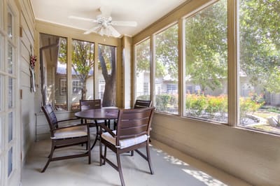 Screened porch area with seating and greenery visible