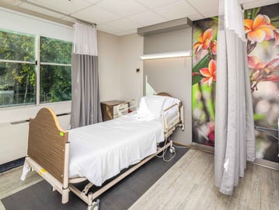 A patient room with a hospital bed and floral decor