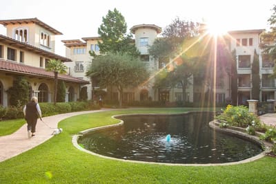 Resident walking a dog near a pond in the courtyard