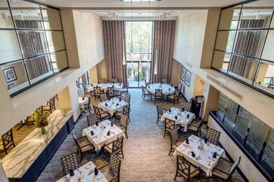 Dining room with tables set for meals overlooking outdoor area